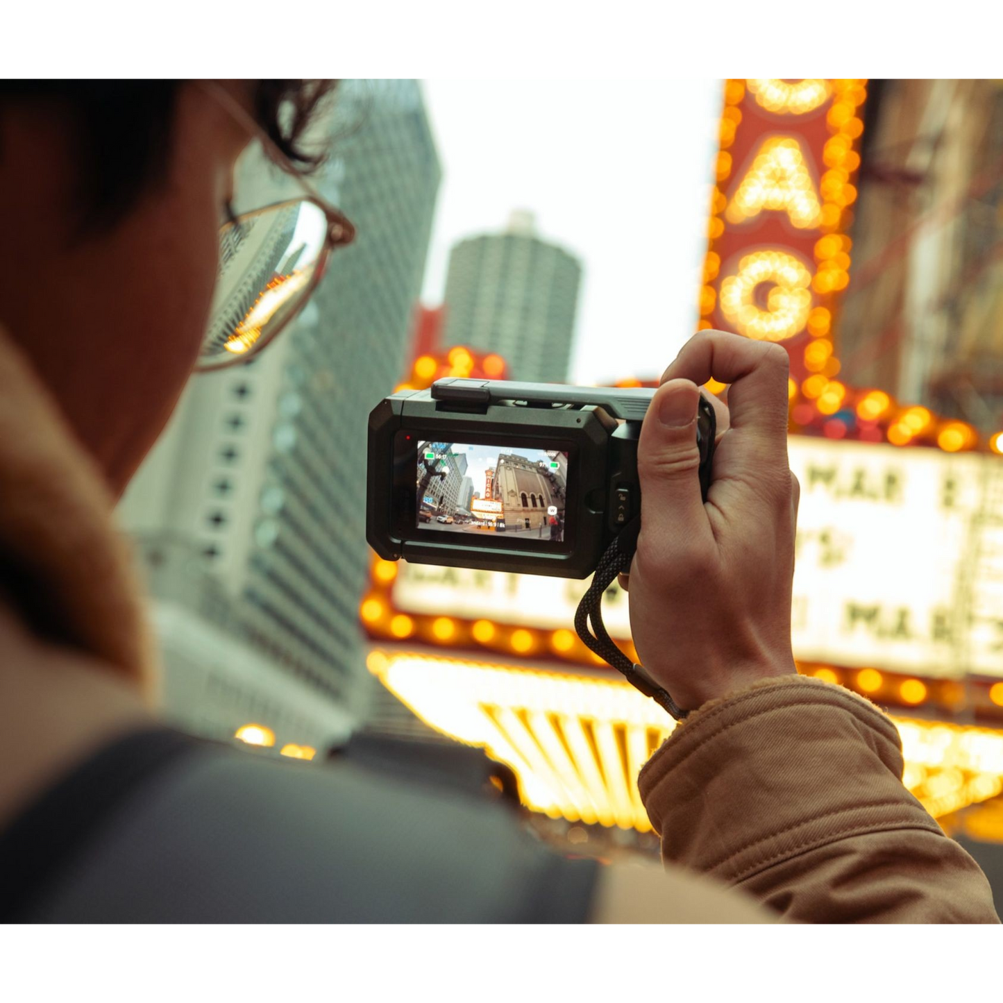 alAsil GoPro MISSION 1 PRO cinema camera held by a creator filming a bright city street scene with neon signs