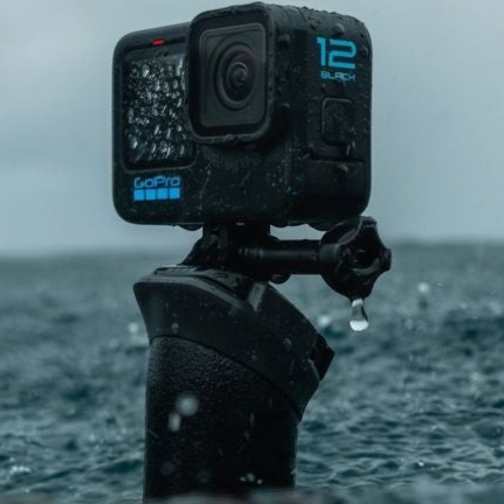 alAsil GoPro HERO12 Black action camera mounted on a grip, wet from rain in a stormy outdoor setting