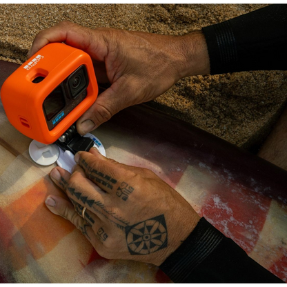 alAsil GoPro HERO12 Black action camera in an orange protective case being mounted to a surfboard on the beach.