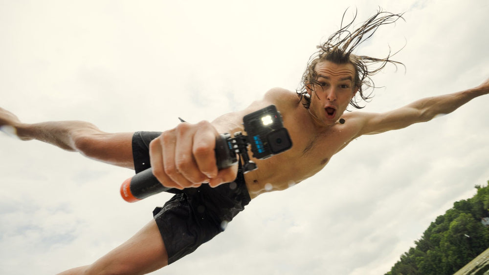 alAsil GoPro LIT HERO action camera with built-in light held by a man jumping into water for low-light filming