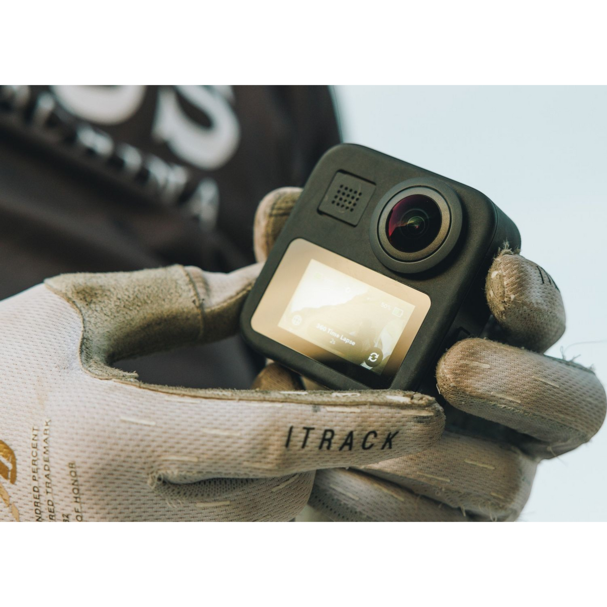 alAsil GoPro MAX 360 camera held in gloved hands showing the front lens and digital display screen