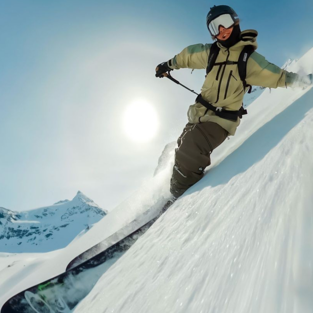 alAsil GoPro MAX2 360 camera capturing a skier carving through deep snow on a sunny mountain slope